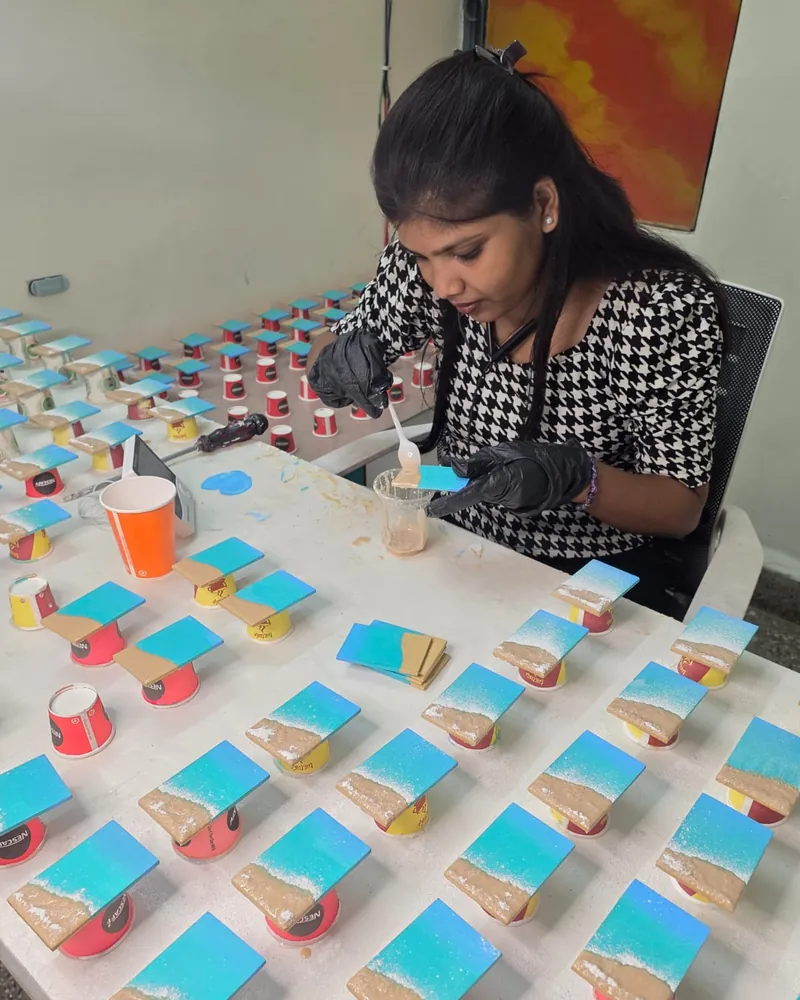 Sakshi pouring resin onto a batch of ocean-style pieces